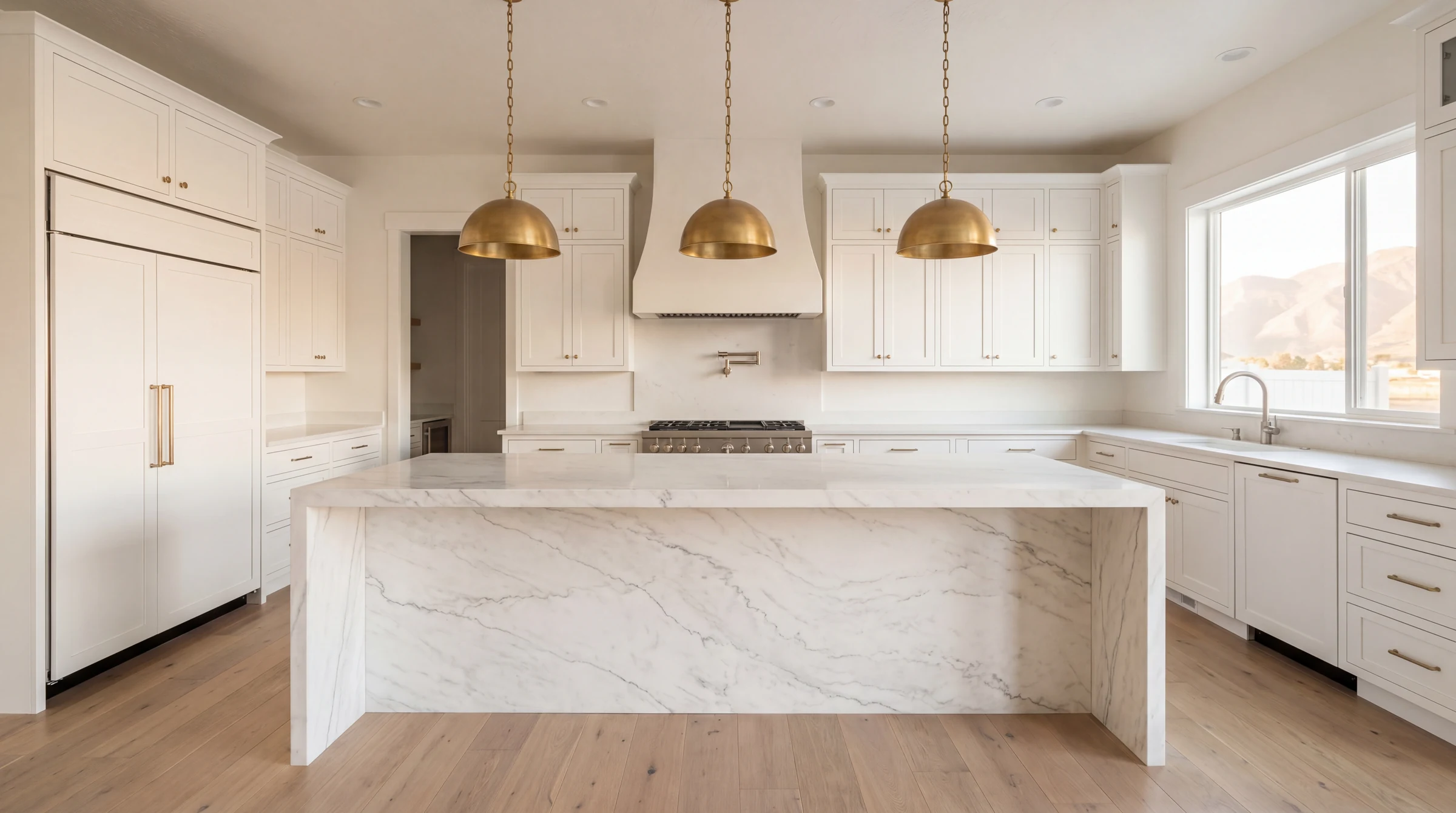 Finished custom Utah kitchen with brass pendants, marble island and white shaker cabinetry